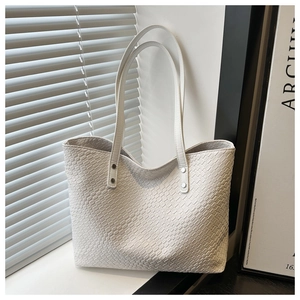 Close-up of white woven texture tote bag featuring silver rivets and durable shoulder straps