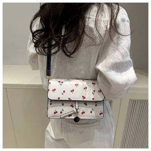 Dettaglio borsa bianca con stampa ciliegie, ciliegie rosse e tracolla sottile nera