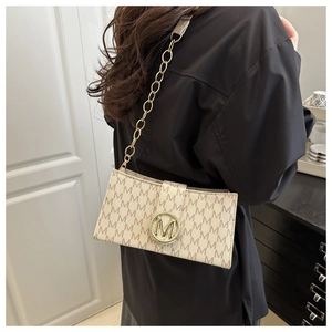 Détail du sac à bandoulière beige avec boucle M dorée et bandoulière en chaîne métallique