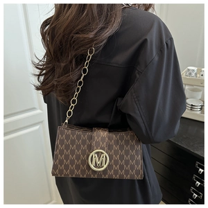 Brown monogram shoulder bag with gold M-buckle and chain strap shown on a model