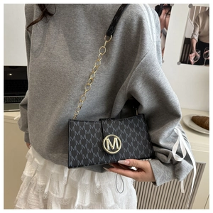 Détail du sac bandoulière noir avec boucle dorée logo M et bandoulière chaîne