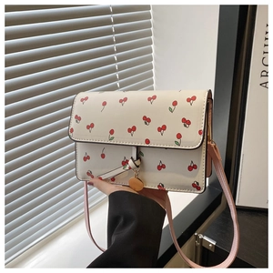 Détail du sac à rabat blanc crème avec imprimé cerises et bandoulière rose