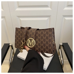 Détail du sac à bandoulière marron avec monogramme et boucle dorée en M
