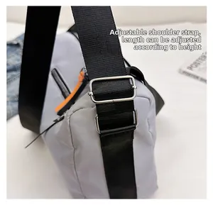 Detail of adjustable nylon strap with silver metal buckle on a grey crossbody bag