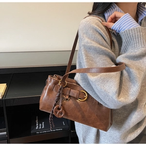 Detail of vintage brown leather-like underarm bag worn over the shoulder with strap