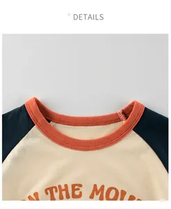 Detail of kids' crewneck tee with navy raglan sleeves and orange ribbed neckline stitching