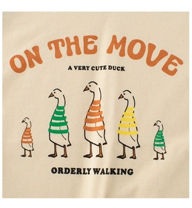 Detail of cartoon ducks print on cream cotton fabric of a girl's short-sleeve t-shirt