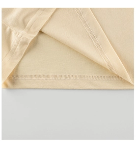 Close-up of double-needle stitching on the hem of a beige knitted kids' cotton t-shirt