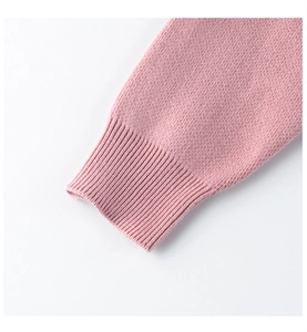 Detalle de los puños de un suéter de punto rosa con acabado elástico y textura suave