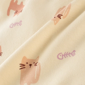 Close-up of soft knitted cotton fabric with cute pink cat and purple fishbone prints