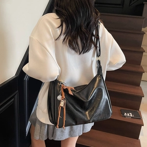 Bolso tote grande negro retro con textura brillante llevado al hombro en una escalera