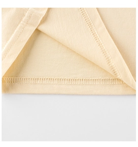 Vue macro des doubles coutures sur le tissu en coton jaune lisse du t-shirt fille