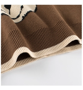 Detail of girls' brown knit sweater featuring ribbed hem and cute bear cartoon pattern