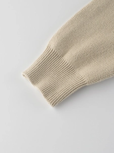 Close-up of beige knit sweater showing rib-knit cuffs and premium fabric texture