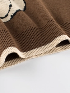 Close-up of knit texture and ribbed cuff on brown cartoon bear sweater for girls