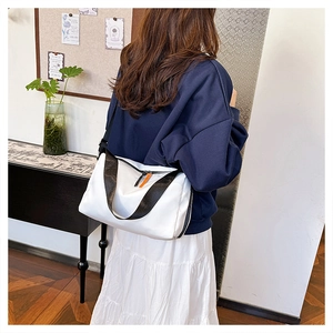 Detailed shot of white water-resistant shoulder bag with black strap and orange zipper puller