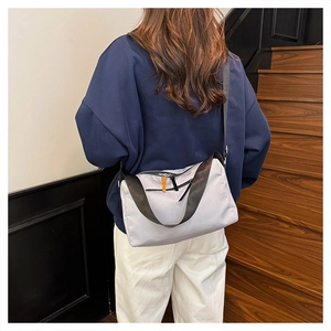 Detail of light gray waterproof nylon crossbody bag with black zipper and wide shoulder strap