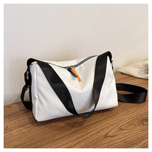 Detail of white nylon crossbody bag with black strap and orange zipper puller