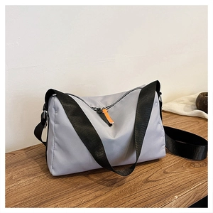 Macro detail of waterproof gray nylon fabric and orange zipper puller on crossbody bag