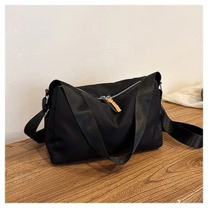 Detail of waterproof nylon crossbody bag with contrasting orange zipper puller