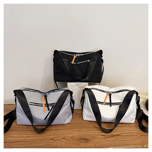 Close-up of nylon crossbody bags in black grey and white with orange zipper pullers
