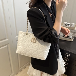 White quilted tote bag with golden chain strap and geometric logo in modern indoor setting