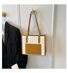 Detail of checkered tote bag with brown leather pocket and Fashion & Bags text