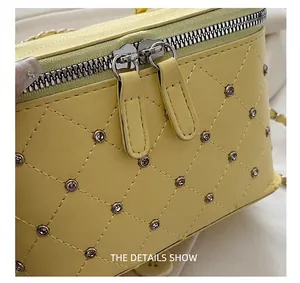 Close-up of quilted yellow leather handbag with silver dual zippers and rhinestone details