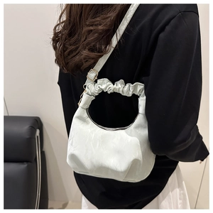 Woman wearing a pleated cloud handle handbag in light green over a black and white outfit