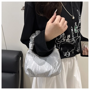 Detail of silver metallic crescent cloud bag with pleated handle shown on model