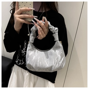 Close-up of a silver metallic pleated handbag featuring a matching scrunchie handle style