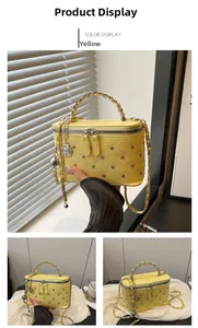 Detail of yellow quilted box bag featuring silver rivets and metal chain handle