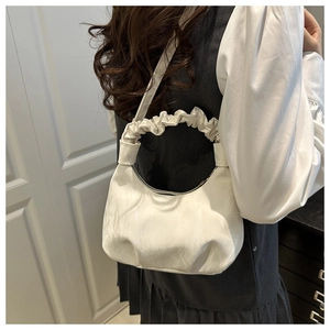 Detail of cream white pleated handle on minimalist cloud-shaped shoulder bag
