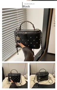 Detail of black quilted leather shoulder bag featuring silver rivets and chain handle