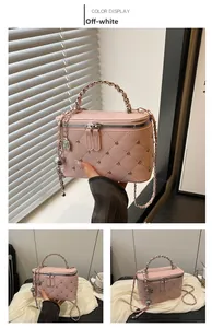 Detail of cream quilted box bag with silver studs, chain strap and dual zipper closure