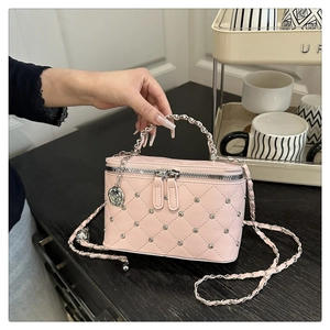 Détail du sac boîte rose matelassé avec rivets argentés et pendentif rose métallique