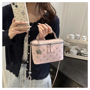 Detailed shot of pink quilted mini box bag with silver studs and metal flower charm