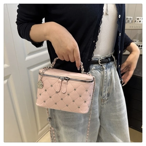 Detail of pink quilted handbag with silver studs and chain strap on a model