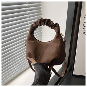 Detail of dark brown crescent bag showing suede texture and pleated cloud handle