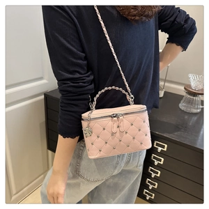 Close-up of pink quilted crossbody bag with silver rivet details and rose pendant