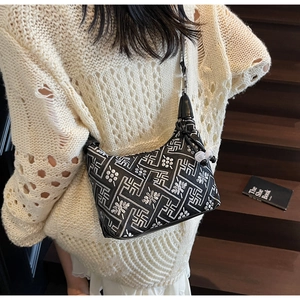 Detail of black shoulder bag featuring silver floral embroidery and beaded zipper charm