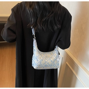 Blue jacquard hobo bag with geometric floral patterns on a model wearing a black coat