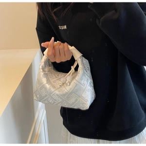 Close-up of elegant floral jacquard fabric and twisted leather handle on underarm bag