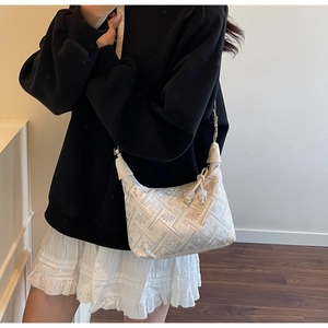 Detail of white satin hobo bag featuring floral jacquard texture and beaded tassel