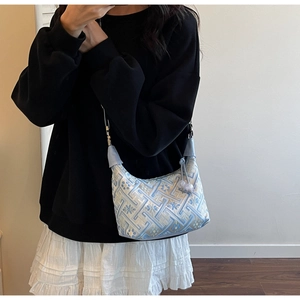 Detail of light blue embroidered jacquard fabric and beaded drawstrings on a hobo bag