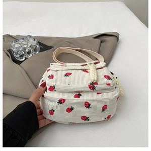 Detail of white corduroy mini bag with red strawberry print and soft fabric handles