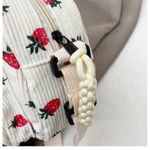 Detail of strawberry print corduroy bag showing zipper texture and woven rope charm