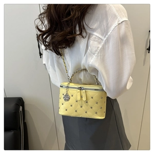 Detail of yellow quilted crossbody bag with silver rhinestones and camellia pendant
