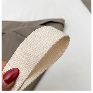 Macro detail of high-density cream woven canvas shoulder strap with reinforced stitching