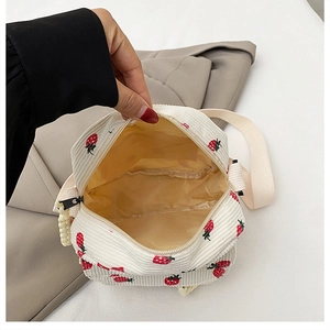 Interior view showing the beige lining and strawberry print of the corduroy crossbody bag